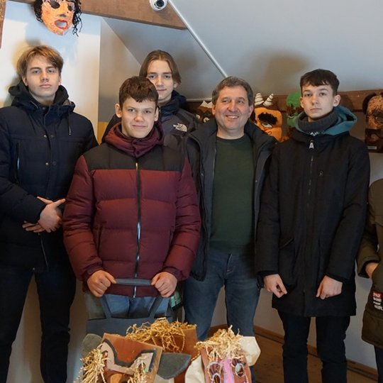 Mokytojas su mokiniais parodoje.
