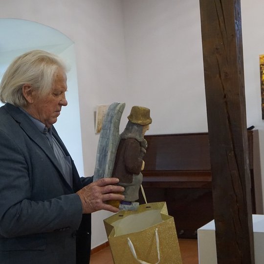 Medžio meistras V. Jaugėla dovanoja parodos autorei medžio skulptūrą